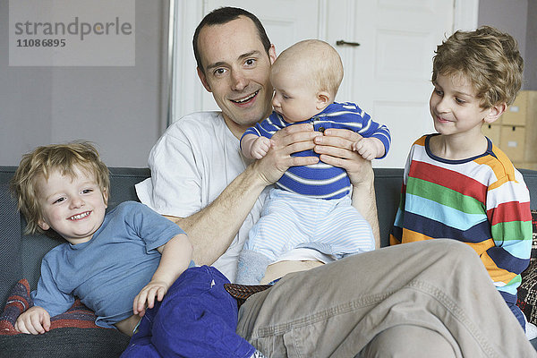 Porträt des lächelnden Vaters mit zu Hause sitzenden Kindern