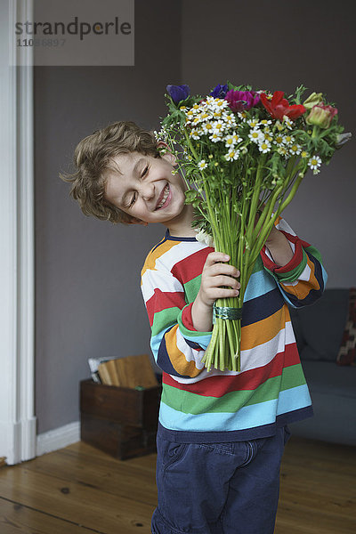 Fröhlicher Junge mit einem Blumenstrauß zu Hause