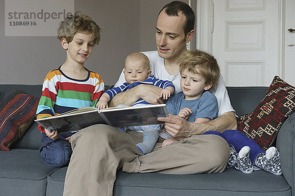 Fröhliches Familienlektürebuch auf dem Sofa zu Hause