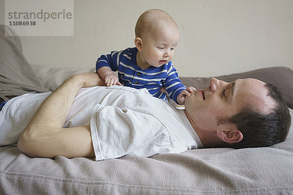 Seitenansicht des Vaters liegend mit Sohn auf dem Bett zu Hause