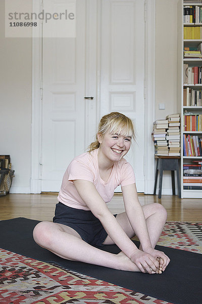 Porträt einer lächelnden Frau  die zu Hause im Wohnzimmer trainiert.