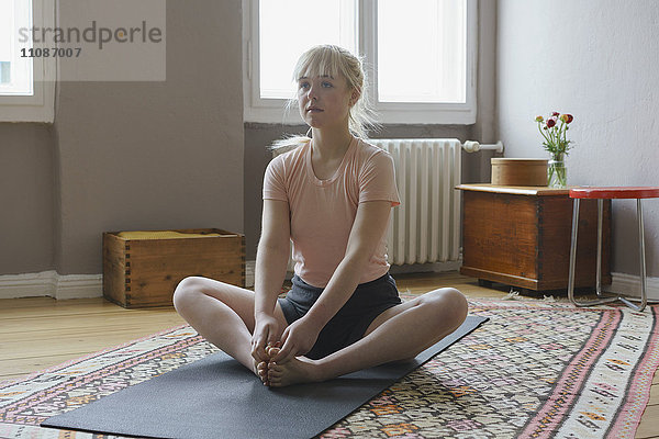 Frau beim Yoga auf der Matte zu Hause