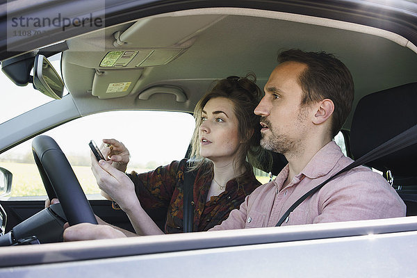 Paar mit Handy zur Richtungskontrolle im Auto