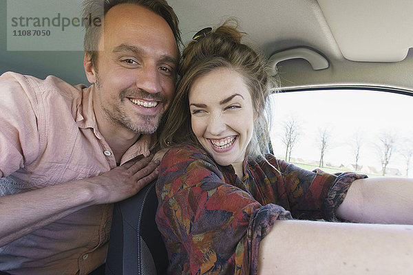 Glücklicher Mann genießt mit Frau beim Autofahren