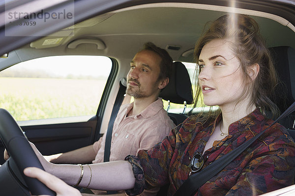 Weibliches Fahren im Sitzen neben dem Mann im Auto