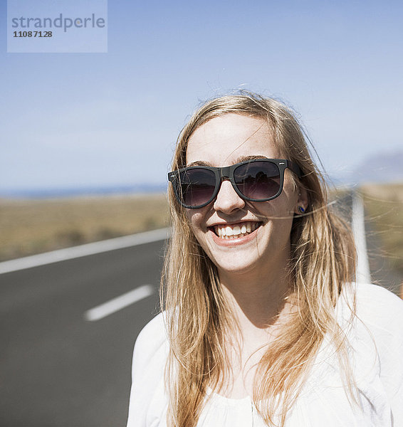 Lächelnde junge Frau mit Sonnenbrille auf der Straße