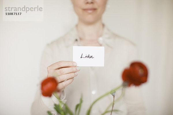 Mittelteil der mittleren erwachsenen Frau mit Liebeszeichen vor roten Blumen