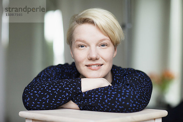 Porträt einer schönen mittleren erwachsenen Frau  die sich zu Hause auf den Tisch lehnt.