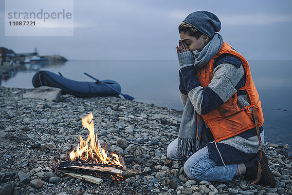 Seitenansicht des Teenagermädchens am Lagerfeuer am Seeufer