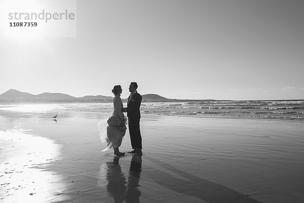 Seitenansicht der Braut und des Bräutigams am Strand