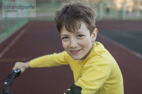 Portrait eines lächelnden Jungen beim Radfahren im Hof