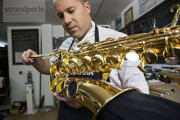 Instrumentenbauer beim Ausbau eines Saxophons während einer Reparatur