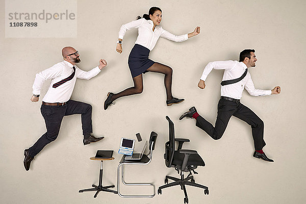 Bürokollegen  die über Stühle und Geräte springen