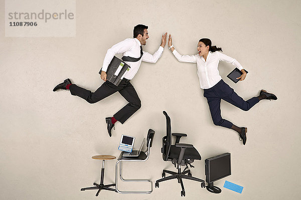 Business-Kollegen fliegen über Stühle hoch fiving