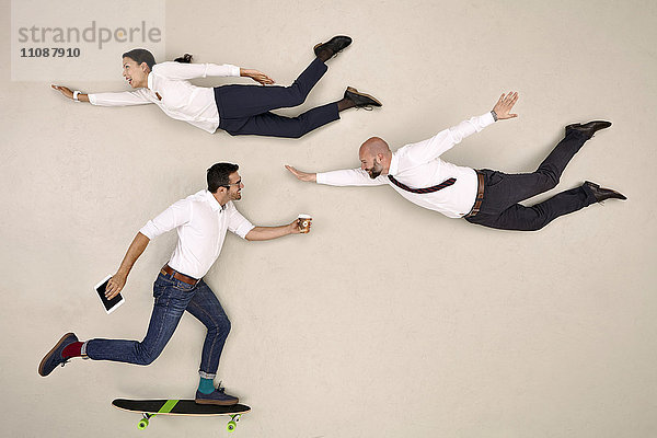 Zwei Geschäftskollegen beim Fliegen  ein Kollege beim Skateboarden