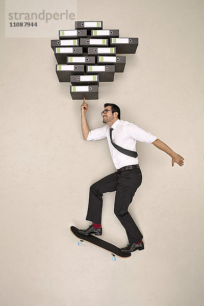 Geschäftsmann Skateboardfahren Balancieren Ordner auf seiner Fingerspitze