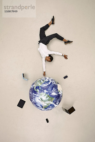 Geschäftsfrau beim Balancieren auf dem Globus mit mobilen Geräten