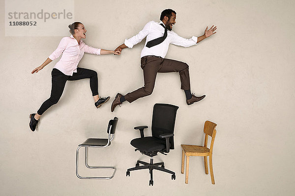 Geschäftsmann springt mit seiner Kollegin über Stühle