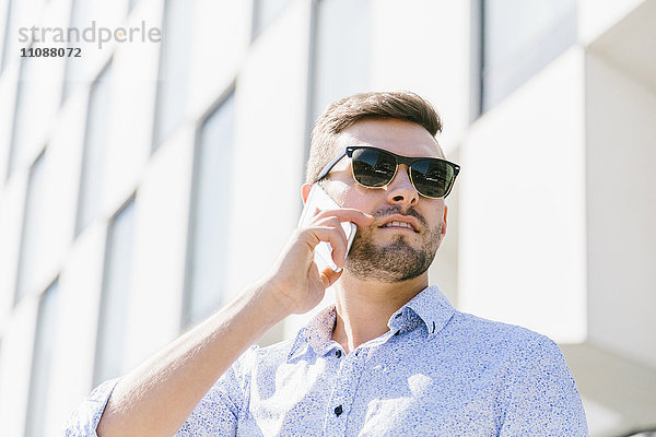 Porträt eines telefonierenden Geschäftsmannes mit Sonnenbrille
