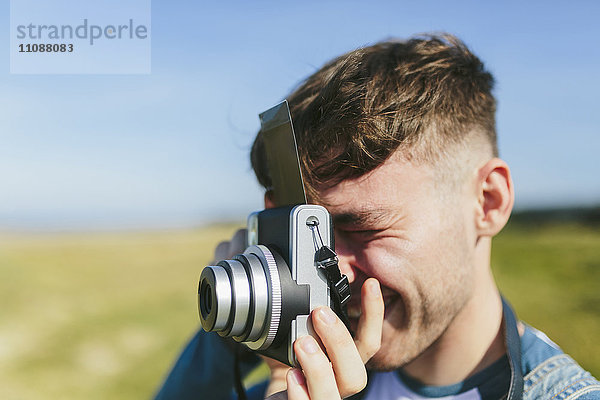 Junger Mann fotografiert mit Polaroidkamera