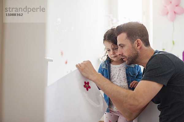 Vater mit Tochter dekoriert Wand im Kinderzimmer