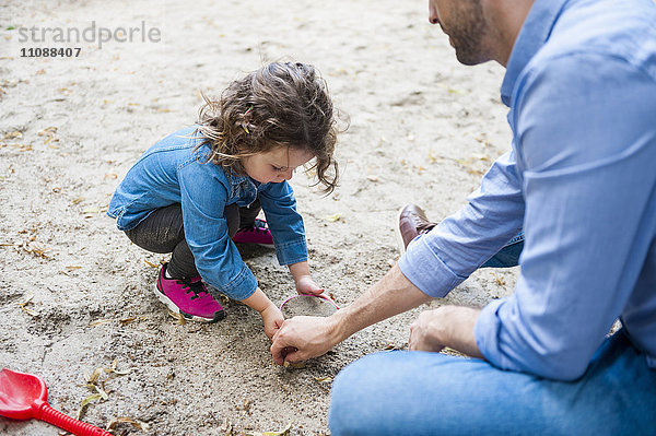 Vater spielt mit Tochter im Sandkasten