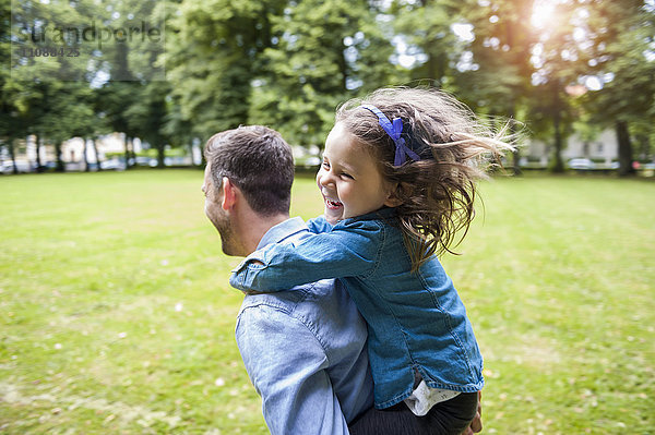 Vater trägt Tochter auf Schultern im Park
