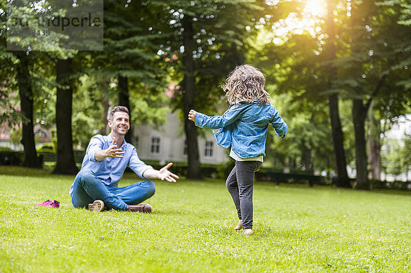 Vater und Tochter spielen auf einer Wiese im Park