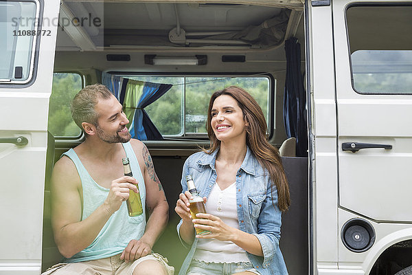 Lächelndes Paar mit Bierflaschen im Van