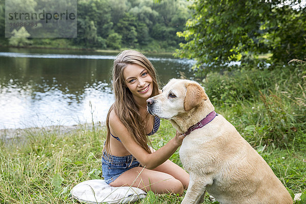 Junge Frau mit ihrem Hund am Ufer des Sees