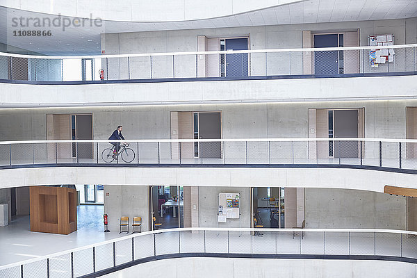 Geschäftsmann auf dem Fahrrad im modernen Bürogebäude