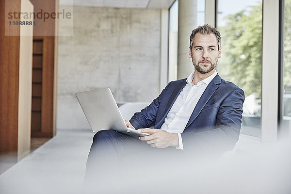 Geschäftsmann sitzend mit Laptop