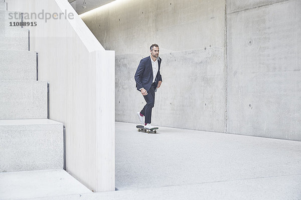 Geschäftsmann beim Skateboardfahren entlang der Betonmauer