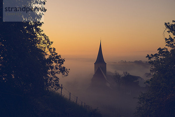 Deutschland  Weinsberg  Kirche bei Sonnenaufgang  Nebel