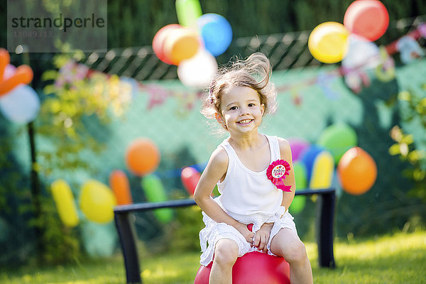 Glückliches kleines Mädchen bei der Geburtstagsparty im Garten