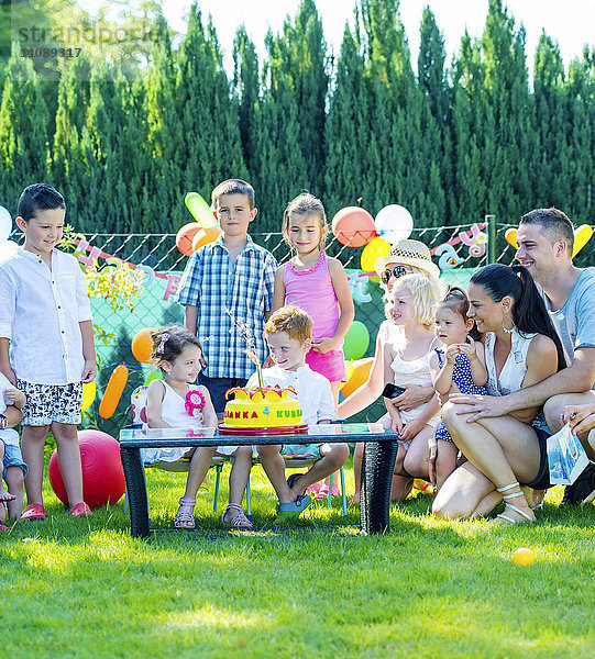 Kinder feiern Geburtstag mit Freunden und Familie im Garten