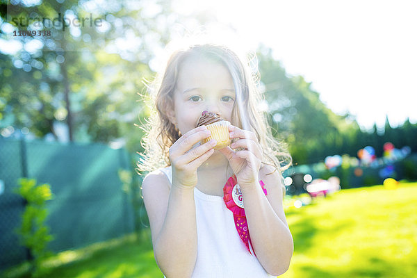 Kleines Mädchen beim Muffinessen im Garten