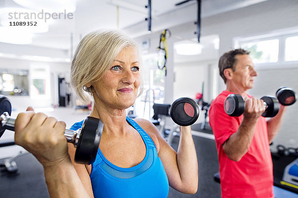Reife Frau und älterer Mann beim Training im Fitnessstudio