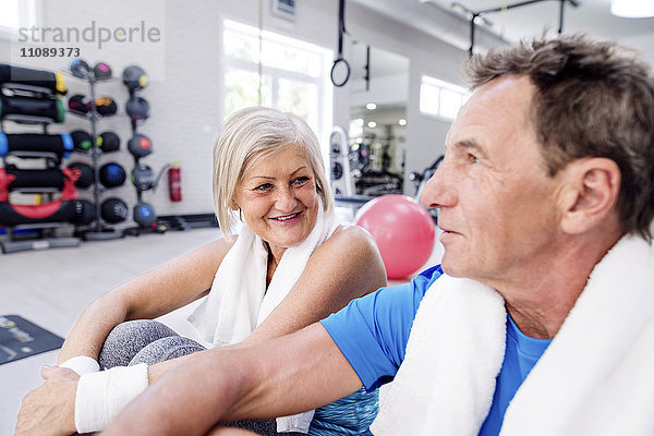 Lächelnde reife Frau und älterer Mann bei einer Pause im Fitnessstudio
