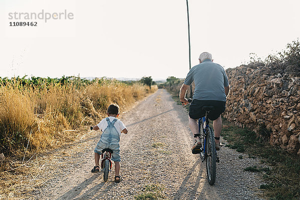 Rückansicht des kleinen Jungen und seines Urgroßvaters auf der Fahrradtour