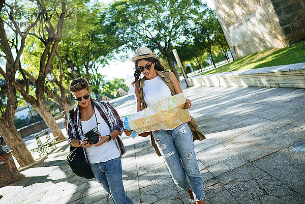 Zwei junge Touristen mit Kamera und Stadtplan beim Rundgang