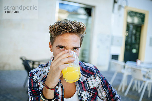 Junger Mann trinkt eine Orangenlimonade