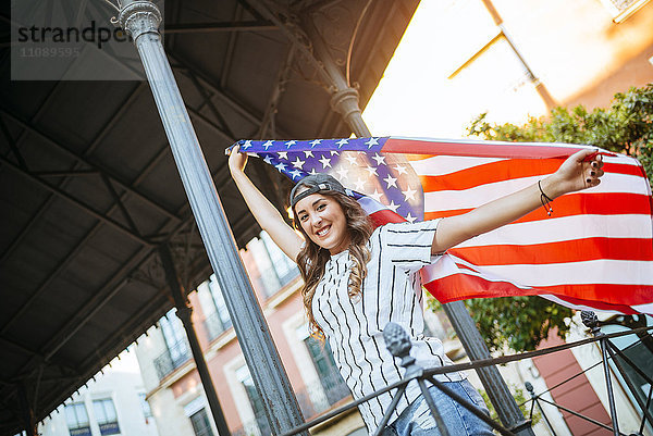 Porträt einer lächelnden jungen Frau mit amerikanischer Flagge