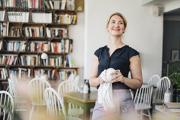 Lächelnde Frau trocknet Tasse in einem Café