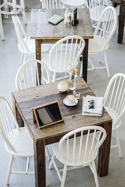Digitales Tablett  Sonnenbrille  Zeitung und Tasse Kaffee auf dem Tisch in einem Cafe