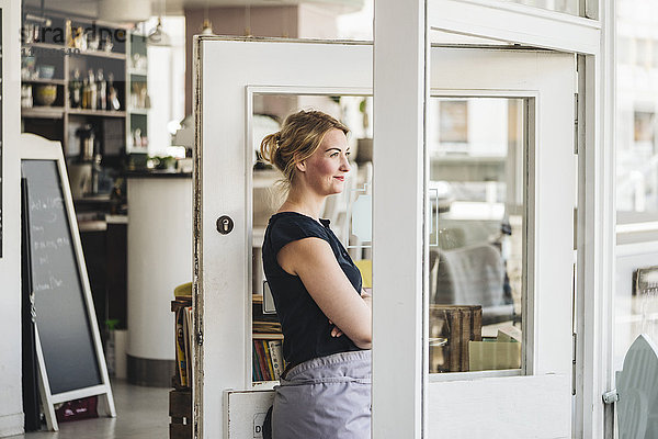 Lächelnde Frau in einem Café mit Blick aus dem Fenster