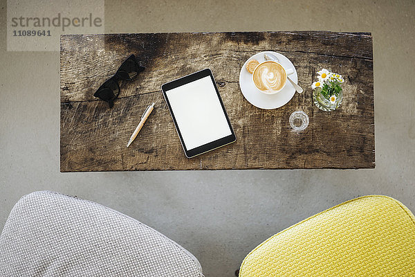 Digitales Tablett  Sonnenbrille und Tasse Kaffee auf dem Tisch im Cafe
