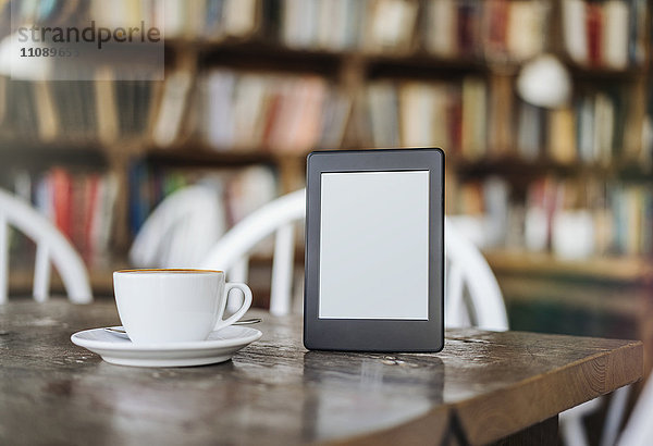 E-Book und Tasse Kaffee auf dem Tisch im Cafe