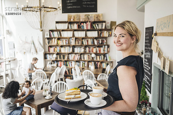 Lächelnde Kellnerin im Café mit Kuchen und Kaffee