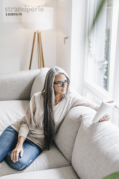 Frau auf der Couch sitzend Lesebuch